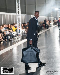 Baba Draman mit dem Anzug Taxi 2-4 Schlitzeanzug Double Press hält Tasche - Model auf dem Laufsteg der Fashionweek Nürnberg - LikeMan Maßanzüge Nürnberg