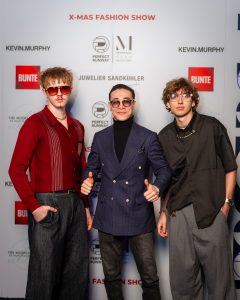 Morteza Faizi Designer auf der X-Mas Fashionweek München vor der Wand mit 2 Models - LikeMan Maßanzüge Nürnberg