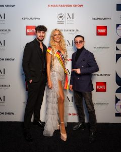 Morteza Faizi Designer auf der X-Mas Fashionweek München vor der Wand mit Monika Leiterin der Fashionweek - LikeMan Maßanzüge Nürnberg